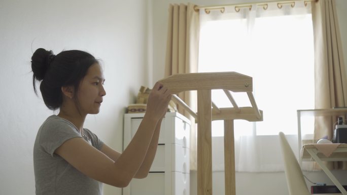 快乐的​ 一个亚洲女孩正在为房子装配新家具