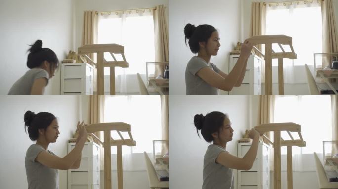 快乐的​ 一个亚洲女孩正在为房子装配新家具