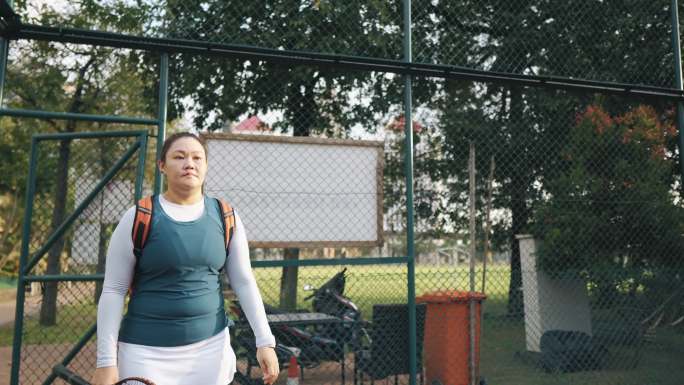 亚裔中国中年女子网球运动员走进网球场