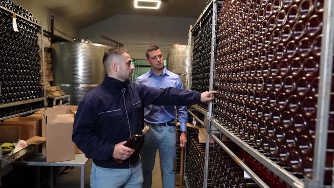 酒厂老板和质量控制专家检查酒窖中的葡萄酒质量