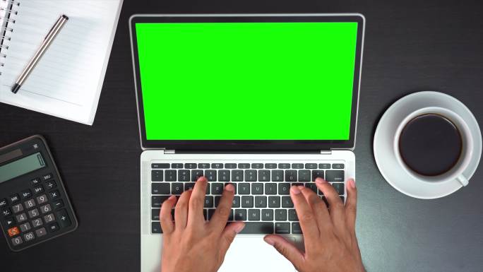 俯视图男性手在笔记本电脑上工作，绿色屏幕位于白色桌面上方
