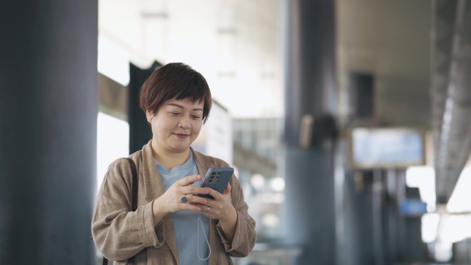 亚洲中国女性使用人脸识别技术解锁手机并打开手机音乐收听应用程序
