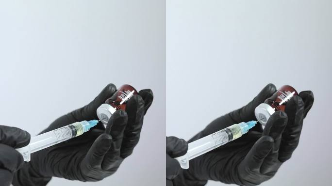 医务人员用手将药物从小瓶中抽出，放入注射器中。