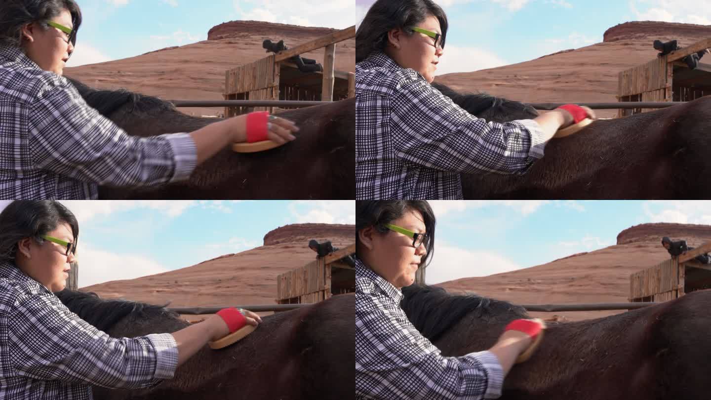 纳瓦霍少女在亚利桑那州纪念碑谷部落公园骑马后用咖喱梳子给马梳洗