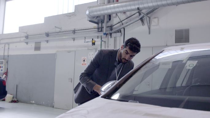 汽车销售员用数字平板电脑在汽车经销商处检查汽车
