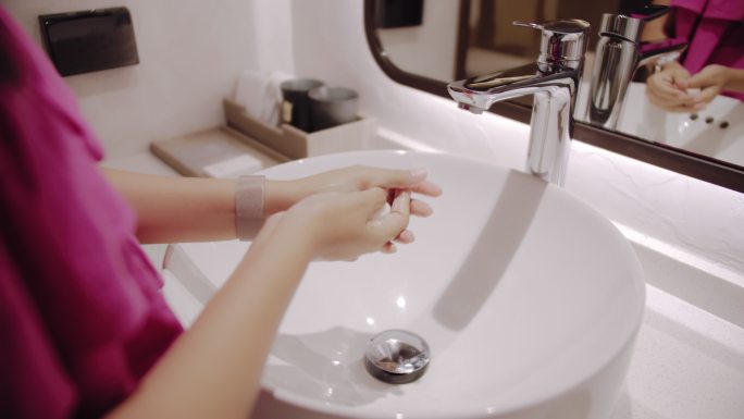 一位女士在酒店房间的洗脸盆前洗手。