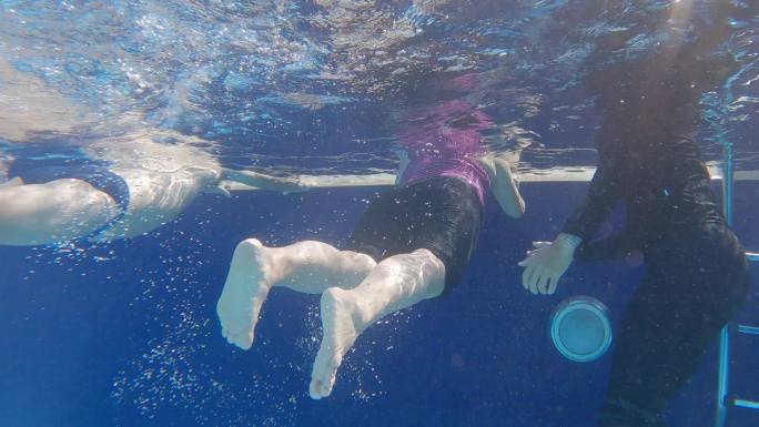 在游泳教练的指导下，亚裔中国高级游泳夫妇在泳池边练习泼水腿