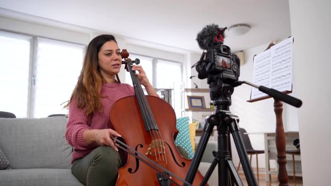 在家里放大提琴时拍摄视频的女人