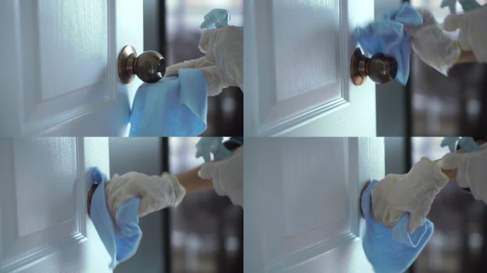 妇女戴着塑料手套，在门把手上喷洒酒精消毒剂，对表面进行细菌或病毒消毒