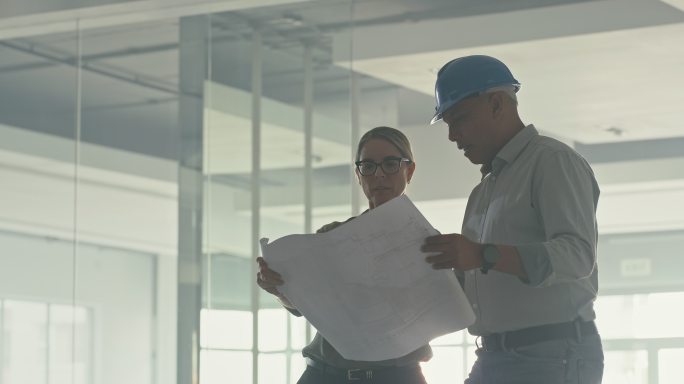 两位建筑师或工程师同事在团队建设项目中设计蓝图。一男一女画建筑平面图