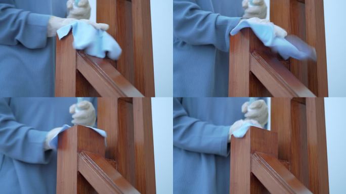 戴塑料手套的女性在楼梯栏杆上喷洒酒精消毒剂，对表面进行细菌或病毒消毒