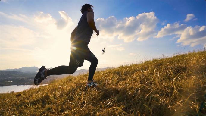 男人山顶向着阳光奔跑户外草地跑步自由运动