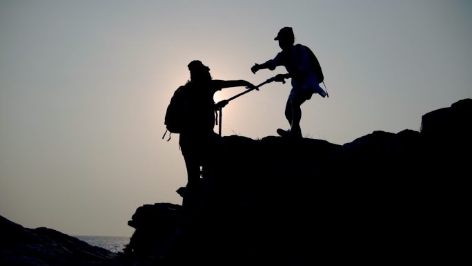 亚洲女子登山帮助朋友登山。