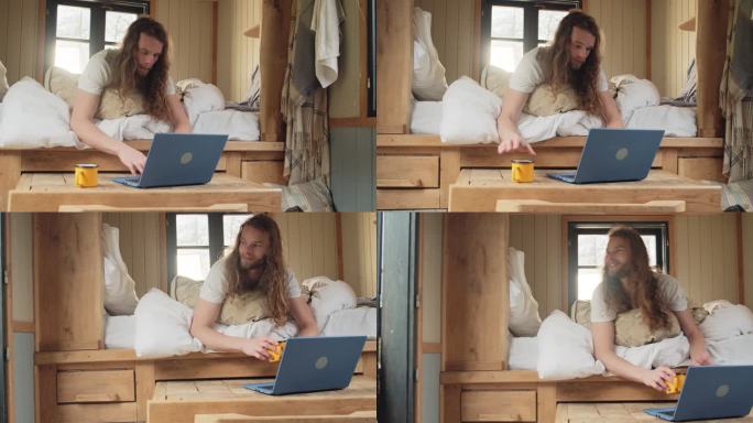 年轻人在小房子度假租赁床上使用笔记本电脑