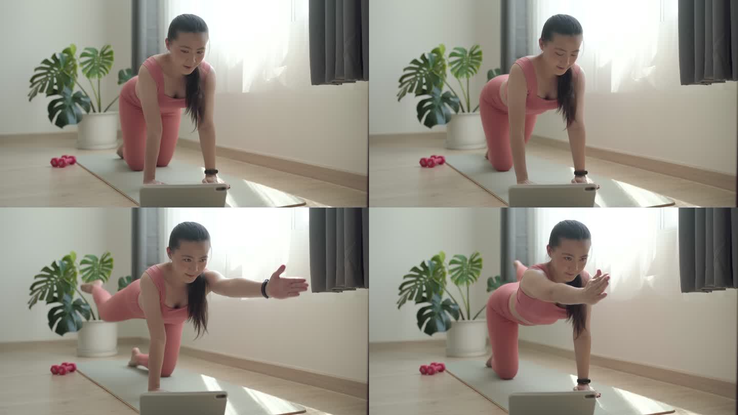 亚洲女性穿着运动服在家里的垫子上锻炼，同时在线观看视频博客。
