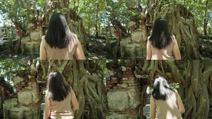 后视图：亚洲中年女性旅行者走过一座被菩提树覆盖的神奇古庙的拱门