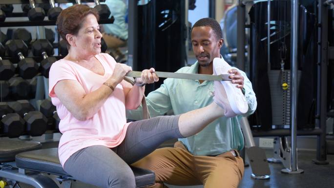 物理治疗师帮助腿部受伤的老年女性