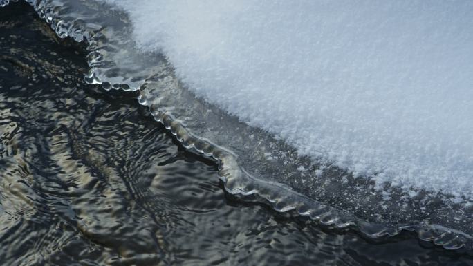 冬季景观。来自山间河流的流水融化了厚厚的白雪的特写镜头。背景。