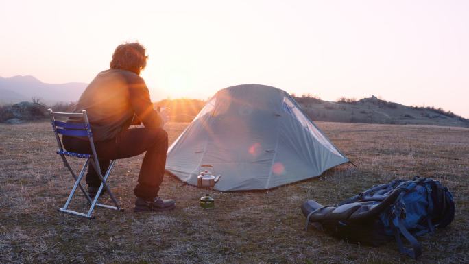 成熟的游客独自在山上露营时喝咖啡。