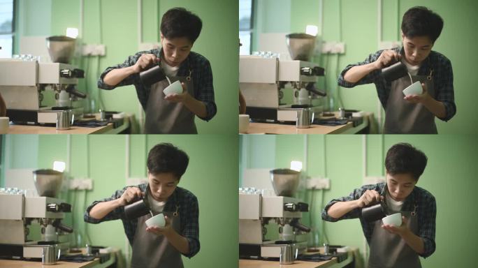 亚洲中国男咖啡师在吧台将泡沫牛奶倒在咖啡杯上准备好的咖啡拿铁艺术品