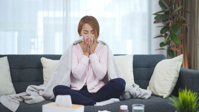 生病的年轻女子盖在毯子上，感觉寒冷和咳嗽，她很冷。感冒、流感、免疫力低下、发烧概念。