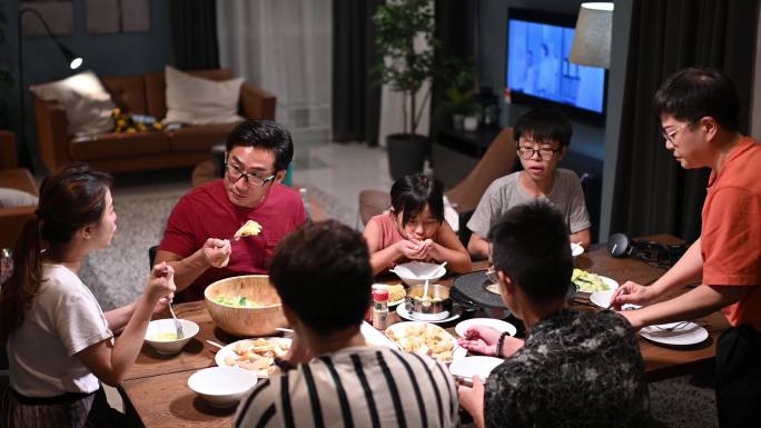 亚裔中国家庭和朋友在家吃晚饭，吃中国传统的轮船菜