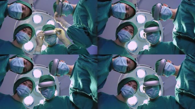 四名外科医生穿着防护服准备手术，他们戴着虚拟现实耳机，俯视手术灯背景上的摄像机。视角概念。
