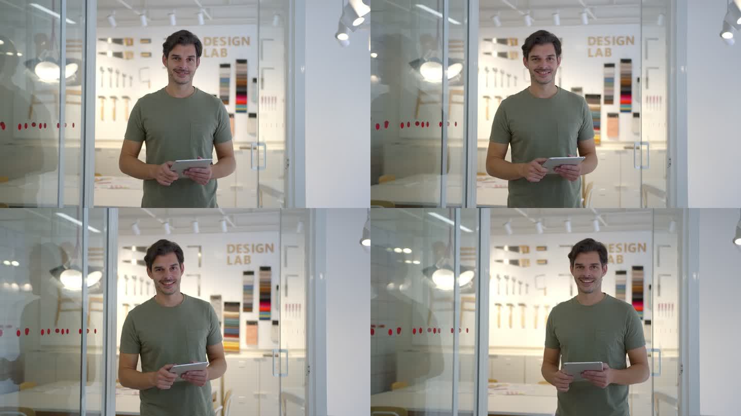 帅气的拉丁美洲男设计师手持平板电脑，看着相机微笑