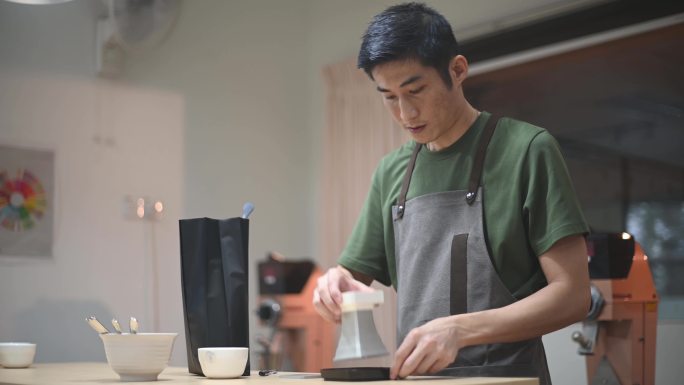 专业亚洲男中式咖啡师准备咖啡杯在明亮的房间里用磅秤称取样品