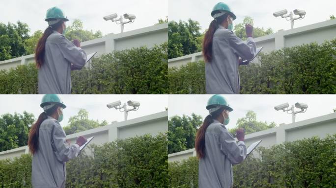 亚洲女性技术检查员检查大楼外的安全摄像头。工程师女性接触