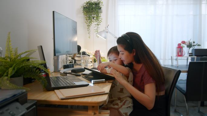 在线怀孕女教师教第一个女儿使用数字平板电脑在家玩教育活动游戏。母亲爱孩子。
