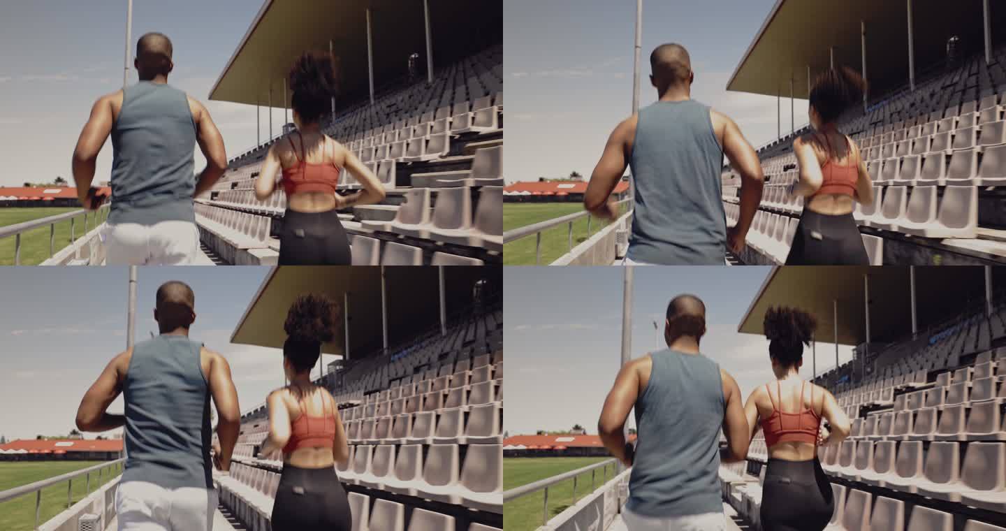 观看两名运动员在体育场并排奔跑，以增强耐力和体能。男女慢跑者穿着运动服在外面跑道上疾跑
