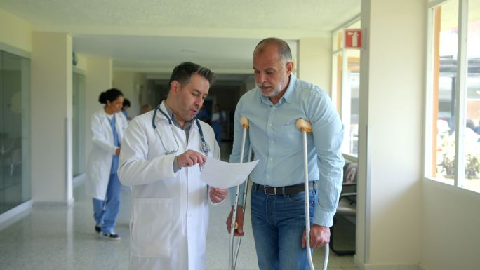 整形医生在医院用拐杖向老年患者解释处方