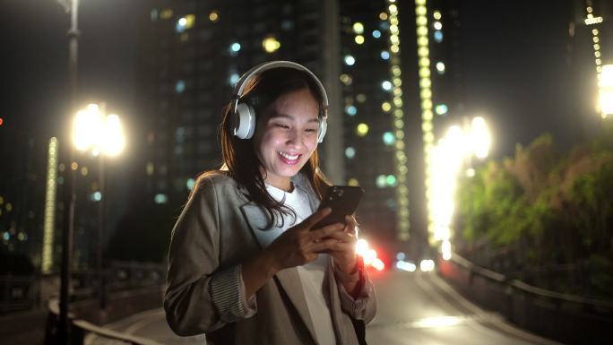 亚洲女性晚上下班后用智能手机听音乐