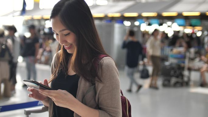 在机场值机柜台使用智能手机的女性