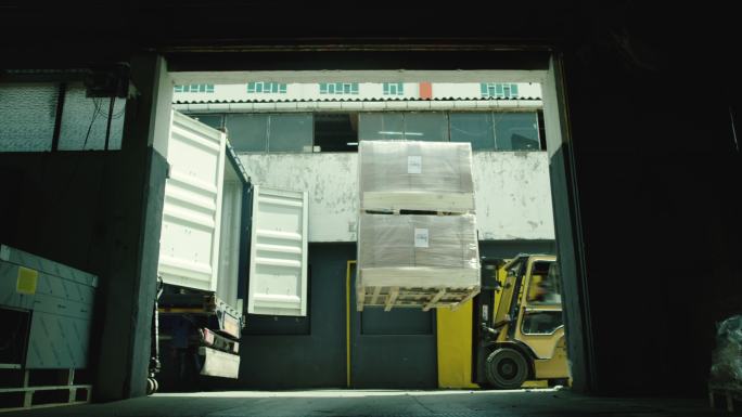 在仓库的卡车上装载产品，叉车从卡车上卸载货物，卡车进入机库卸载和装载货物
