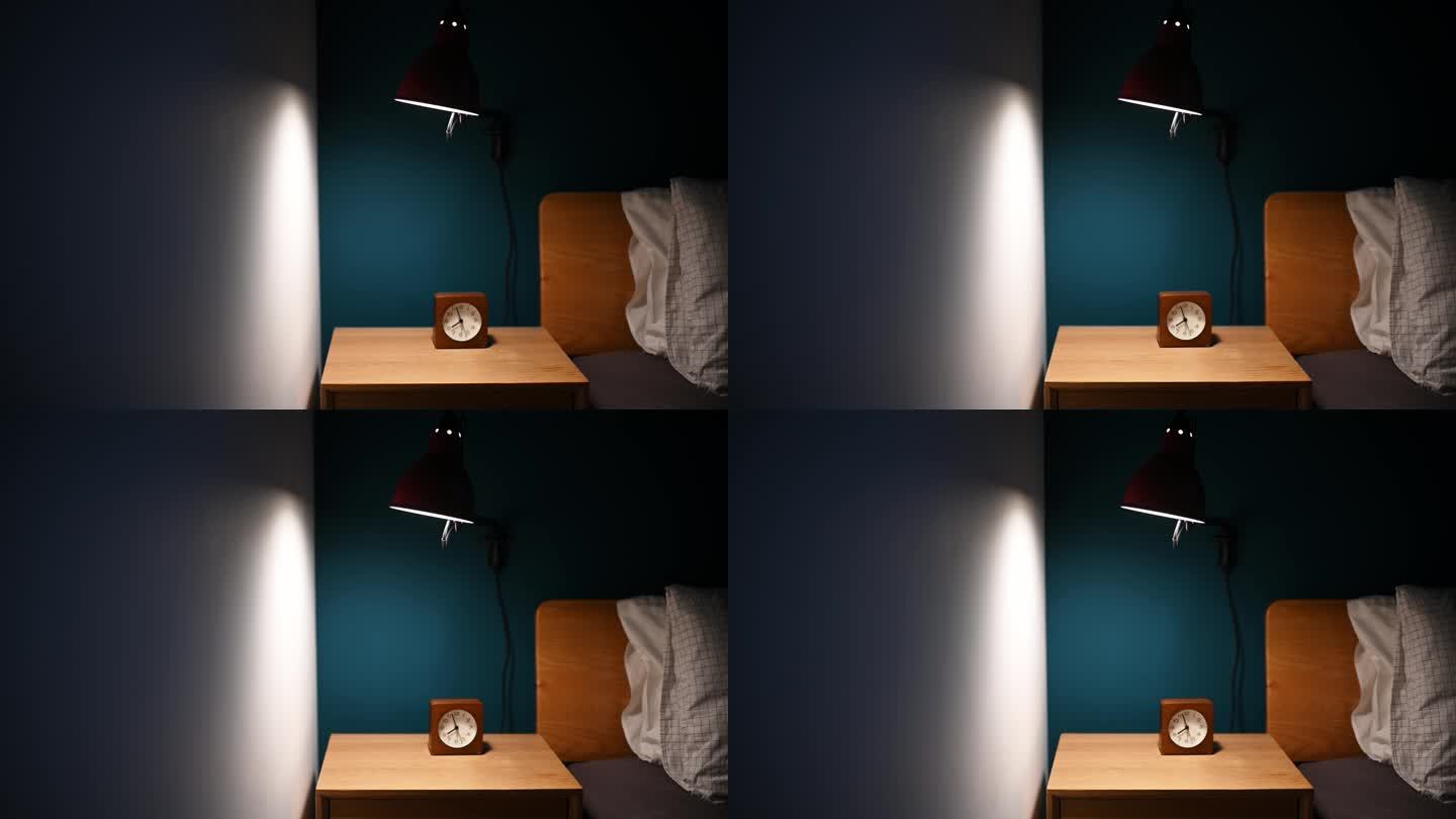 夜间卧室由电灯照明，床头柜上有时钟，床边有蓝色墙壁