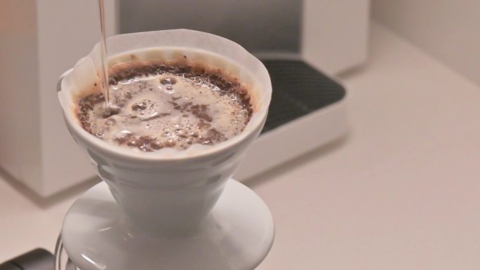 咖啡工艺用咖啡过滤滴头将热水倒入磨碎的咖啡粉中，用于咖啡师早晨的酿造