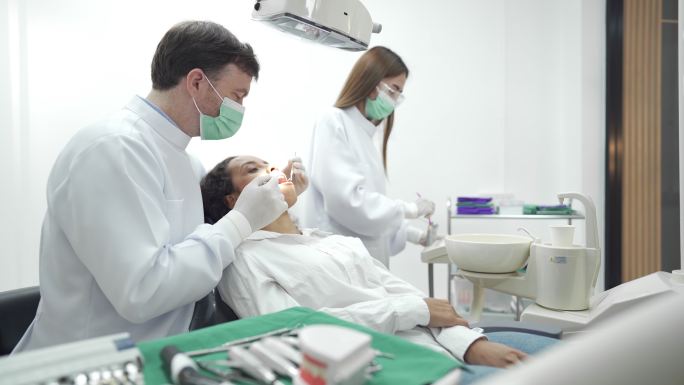 男性牙医检查女性患者的牙齿