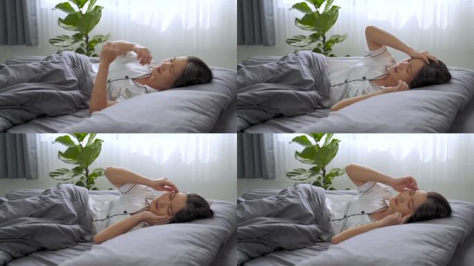 早上躺在床上的一位亚洲妇女因头痛而生病。