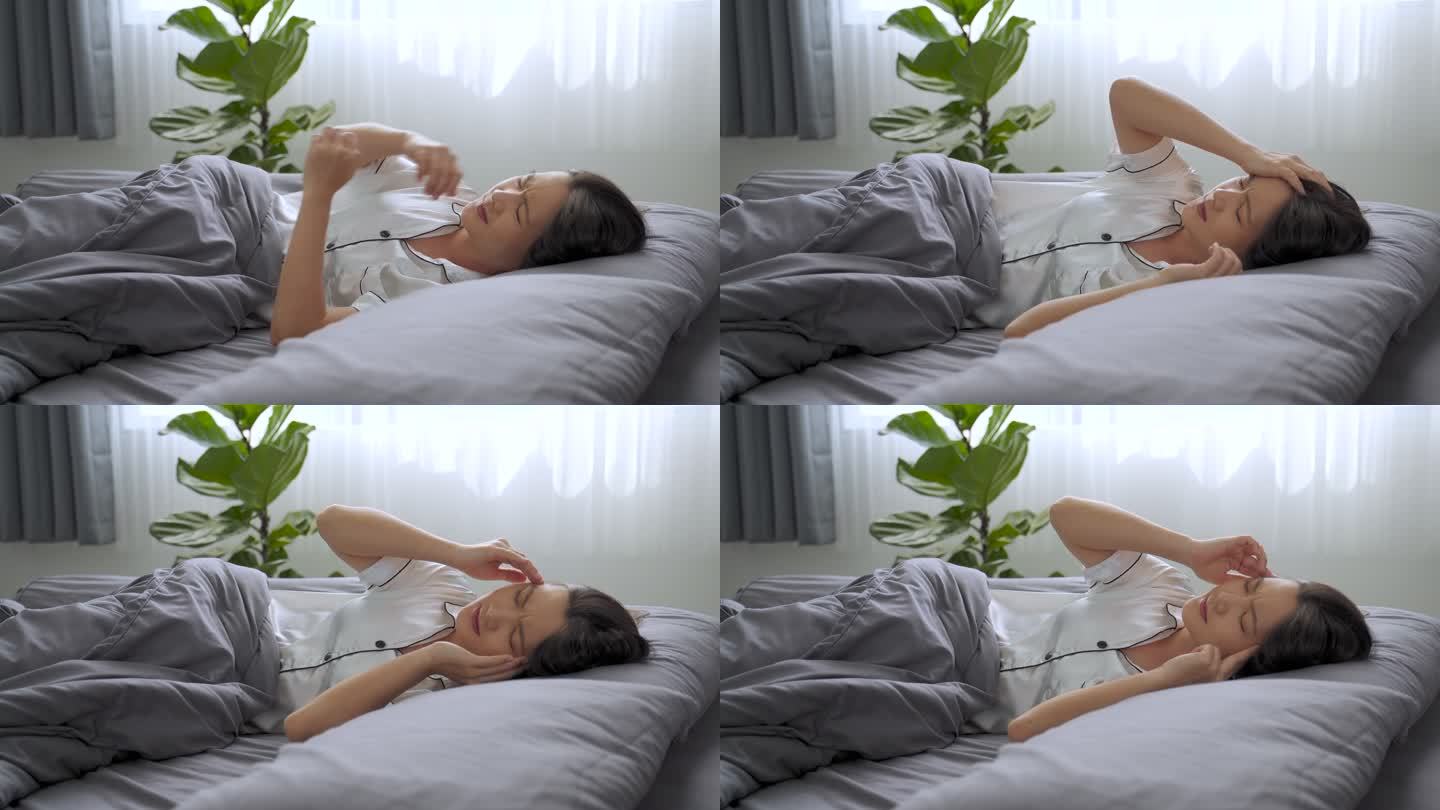 早上躺在床上的一位亚洲妇女因头痛而生病。