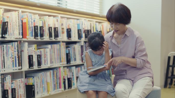 MLS资深女士在图书馆教她的孙女读书