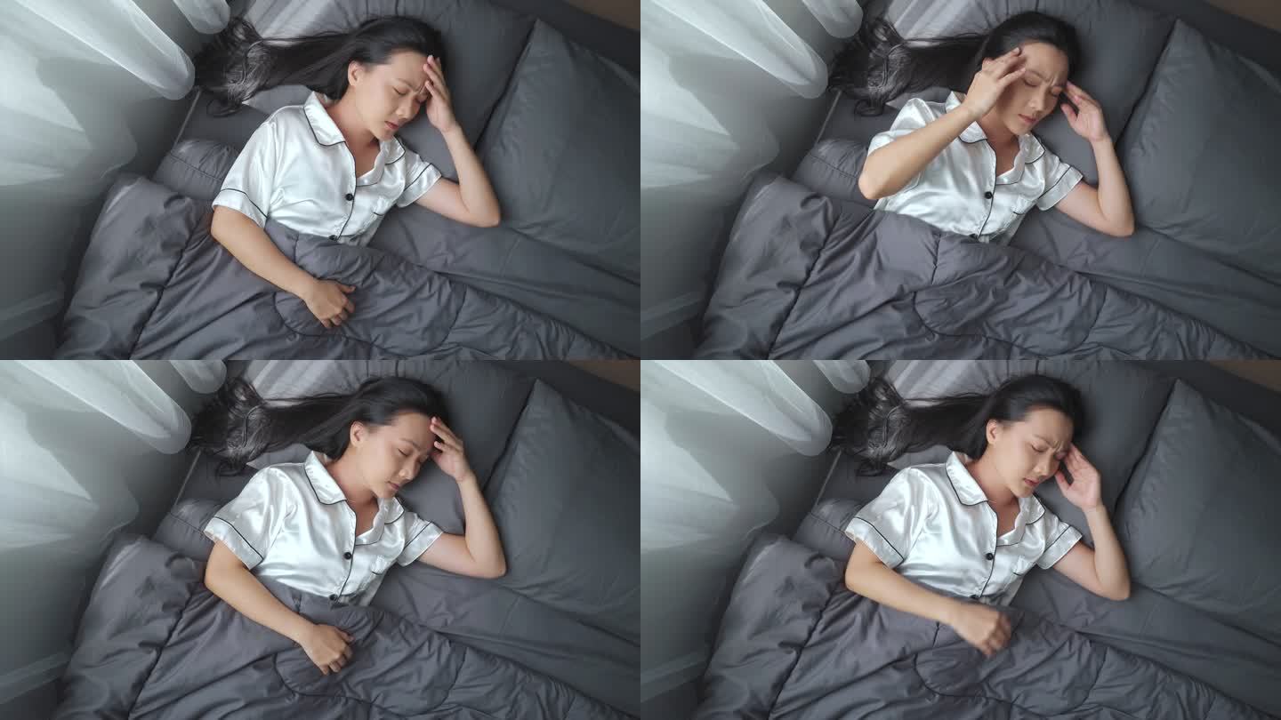 早上躺在床上的一位亚洲妇女因头痛而生病。俯视图。