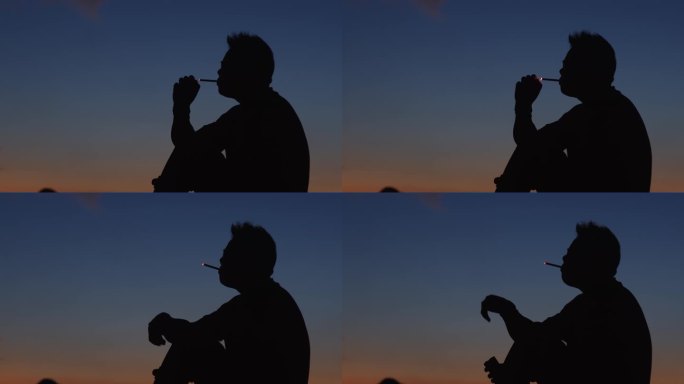 男人坐在山顶抽烟夕阳剪影