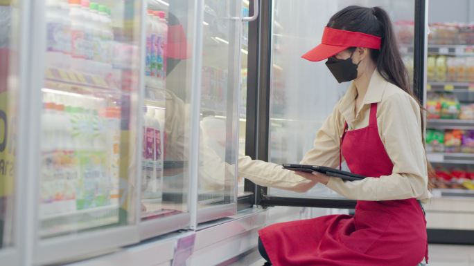 亚洲女超市员工使用平板电脑检查冰箱中的新鲜食品