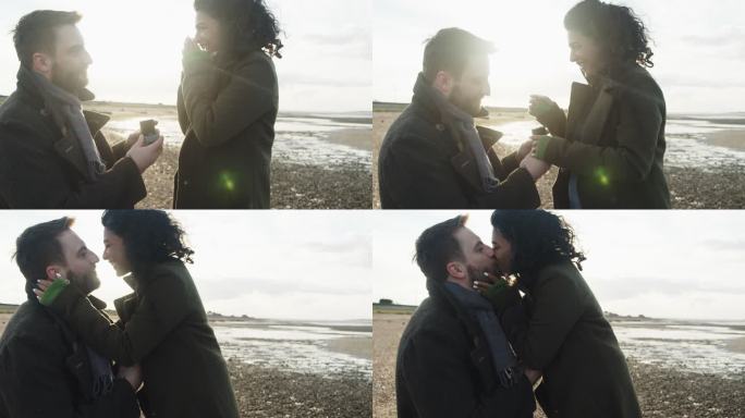 带着订婚戒指的男人在阳光明媚的冬季海滩向女友求婚