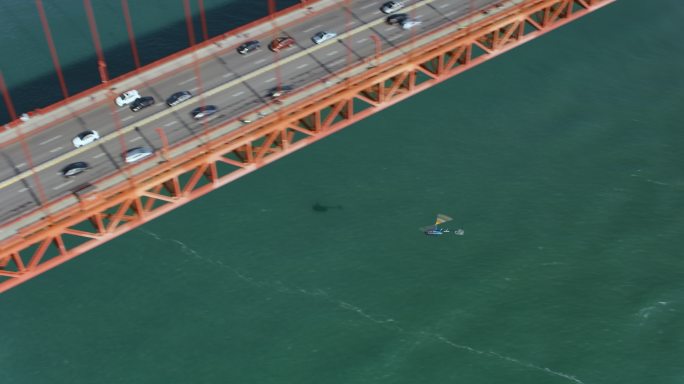 阳光下，空中直升机在加利福尼亚州旧金山金门大桥下飞行