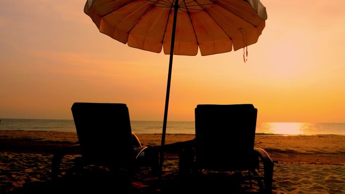 泰国华欣日出的白色沙滩上，带着阳伞的沙滩椅。
