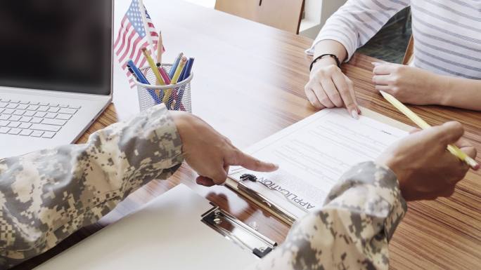 军队招募人员帮助年轻女性填写申请表