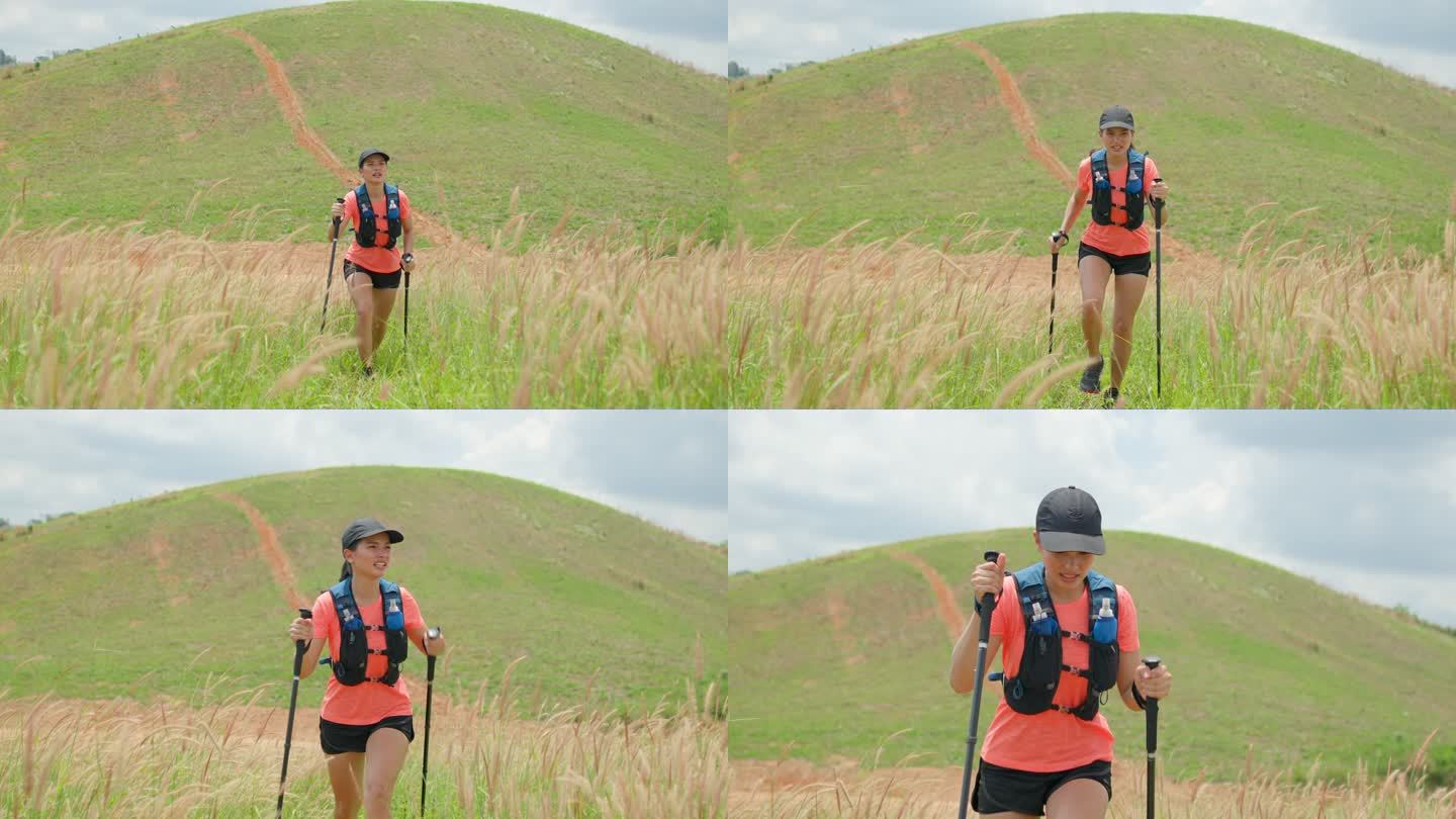 年轻女子在下午的山顶上进行积极的越野跑，超级马拉松选手在户外用徒步杆子冒险